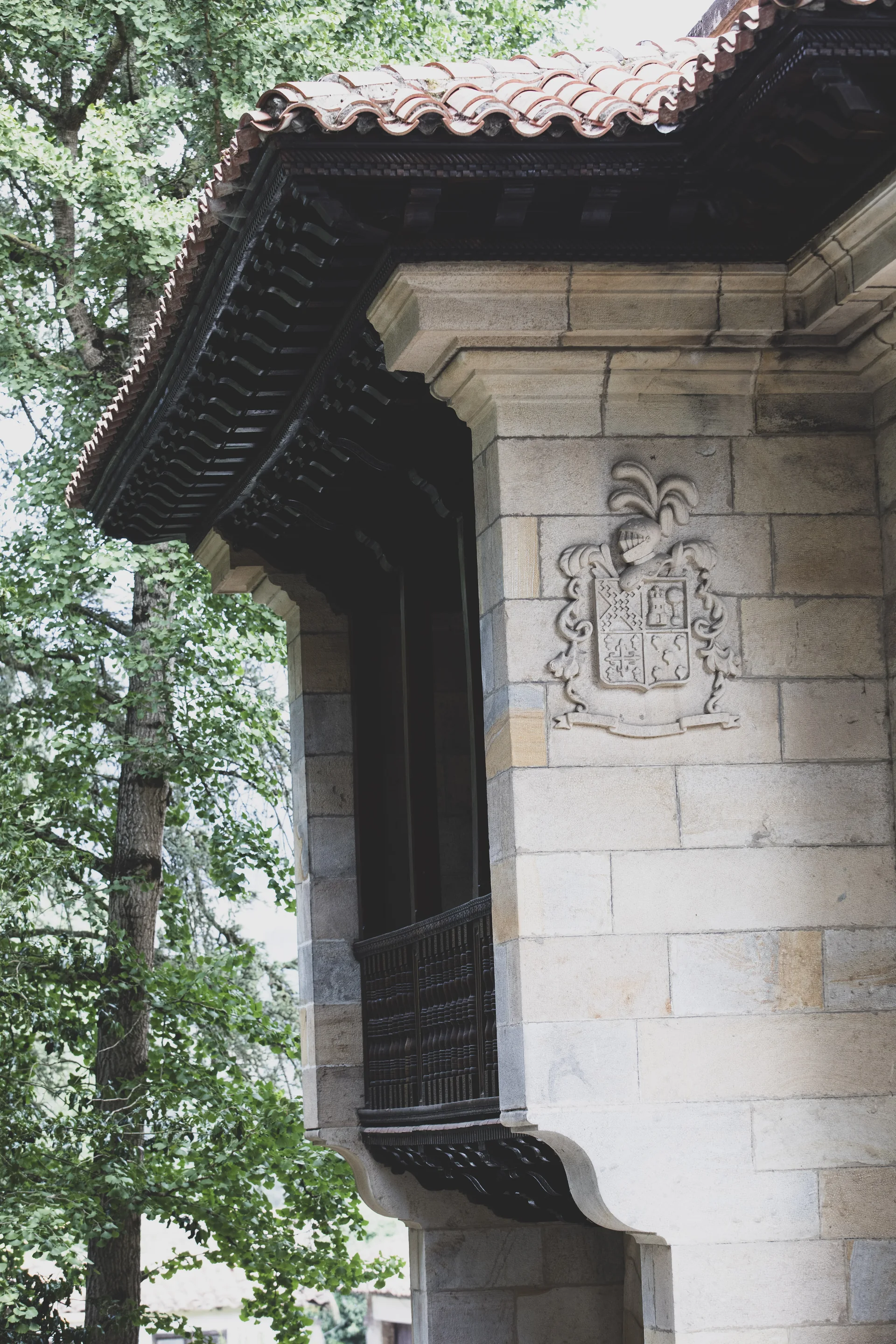 Escudo labrado en la fachada de piedra junto a una balconada de madera.